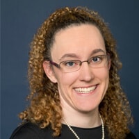 Headshot of Ms. Meg Dowell, she has curly brown hair and is wearing glasses